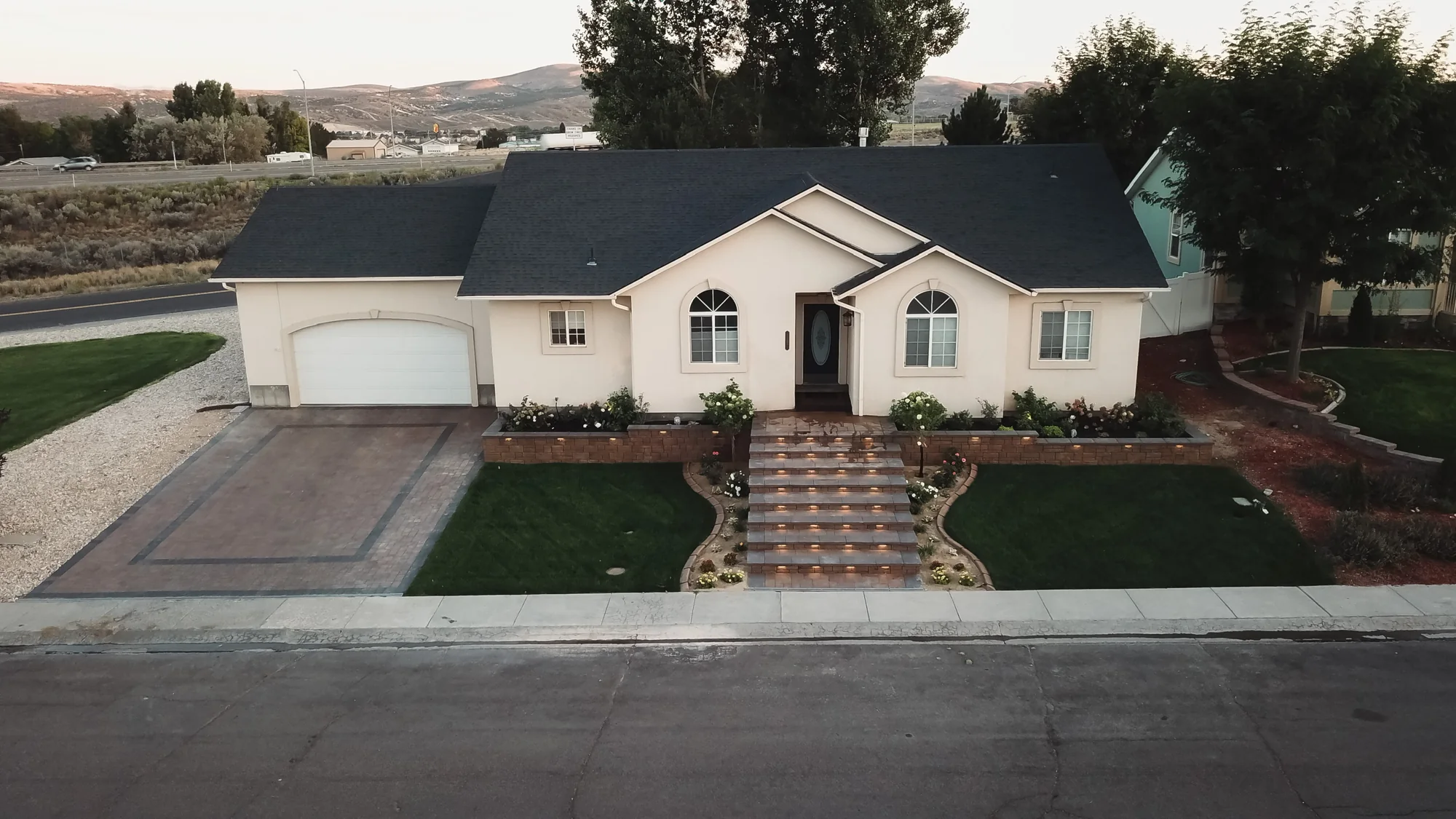 Aerial view of front lawns divided by a central stepped walkway with planted beds beside the house.